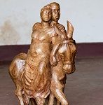 Wooden sculpture of man supporting woman on a donkey